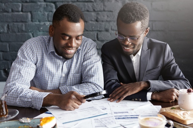 happy-african-american-office-workers-dressed-formal-clothing-having-cheerful-looks-studying-amalyzing-legal-documents-table-using-magnifying-glass-while-getting-papers-ready-meeting_273609-314